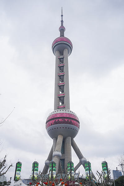 上海東方明珠的低角度拍攝，顯示其獨特的球形與圓柱結構，背景為陰雲密布的天空。