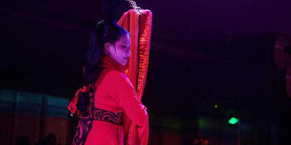 上海宮宴沉浸式餐廳表演：一位身穿華麗紅色漢服的女性舞者，展現優美的古代宮廷舞蹈姿勢
